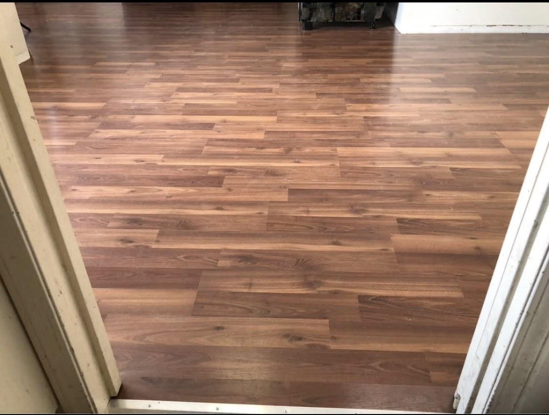 Room viewed through a doorway with rich walnut-toned plank flooring