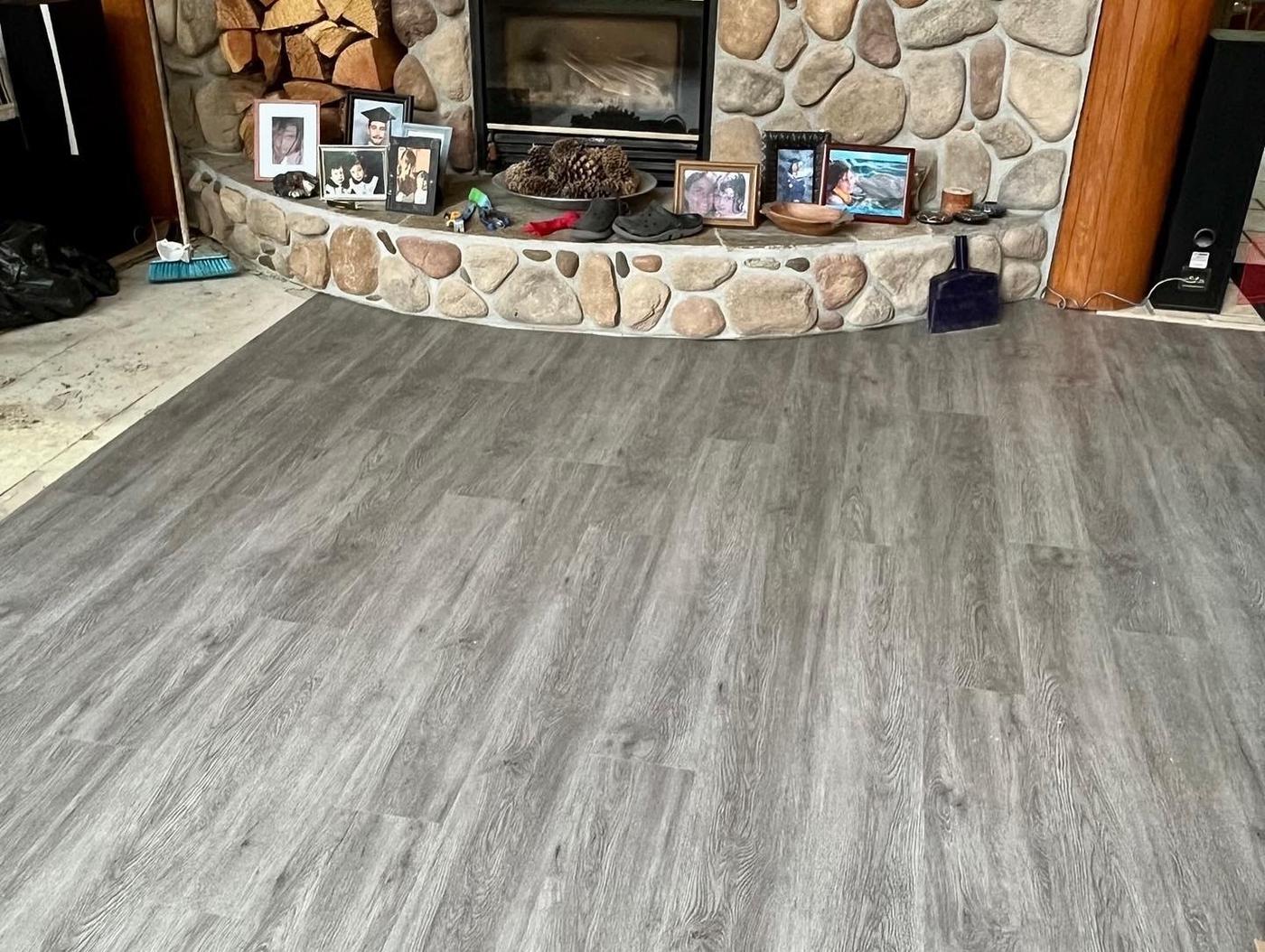 Rustic stone fireplace room with grey wood-look plank flooring